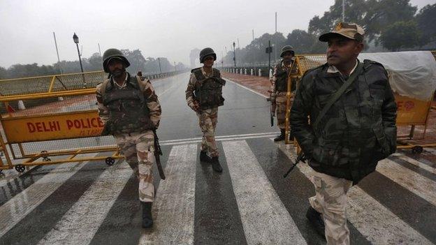 Indian security personnel keep guard in front of India Gate as it rains in New Delhi January 22, 2015.