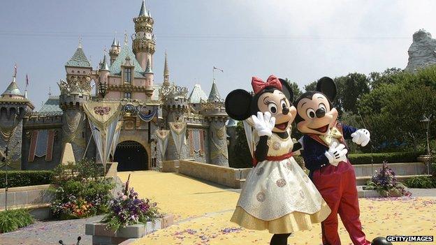 Mickey and Minnie Mouse stand outside Cinderella's castle at Disneyland.