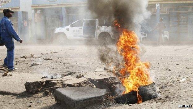 A man walks past a tyre set alight during a nationwide protest as opposition parties tried to block a change in the law that may delay elections - Goma, DR Congo, 19 January 2015