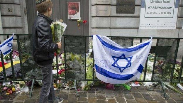 A Jewish boy stands with flowers in front of an Israeli flag and flowers laid in front of the Jewish Museum in Brussels on 26 May 2014