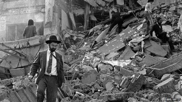 A man walks over the rubble left after a bomb exploded at the Argentinian Israelite Mutual Association (AMIA) in Buenos Aires on 18 July 1994