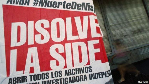 A woman walks behind a poster that reads "Dissolve the SIDE" in Buenos Aires on 26 January , 2015