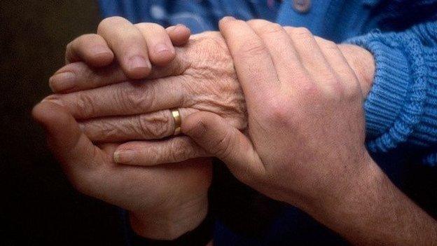 Person holding elderly woman's hand