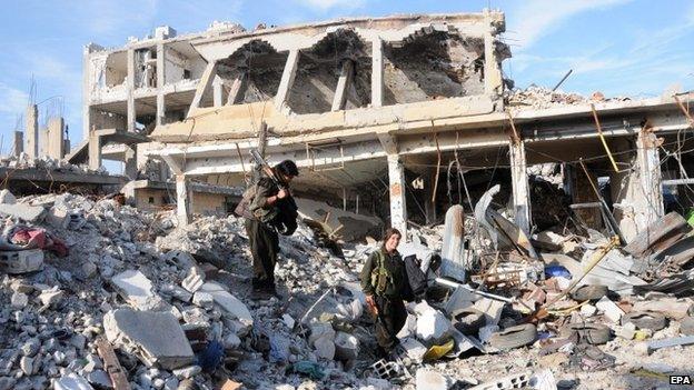 Militants from the Syrian Kurdish YPG group walk through rubble in Kobane, Syria, on Tuesday