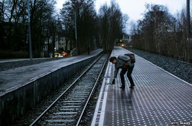 A woman leaves a rose next to one of the many plaques detailing transports of Berlin Jews to concentration camps at Track 17 in Berlin, 27 January