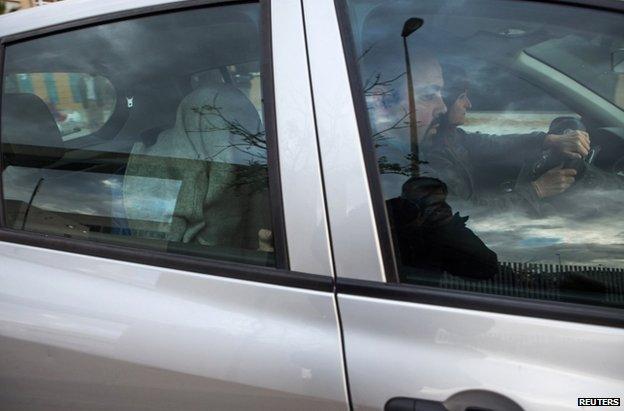 A person believed to be one of the suspects sits with their head covered in the back of a police car in Granada, Spain, 24 November