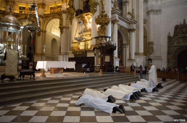 The Archbishop of Granada, Francisco Javier Martinez, and fellow priests prostrate themselves in front of the altar of Granada's cathedral, 23 November 2014