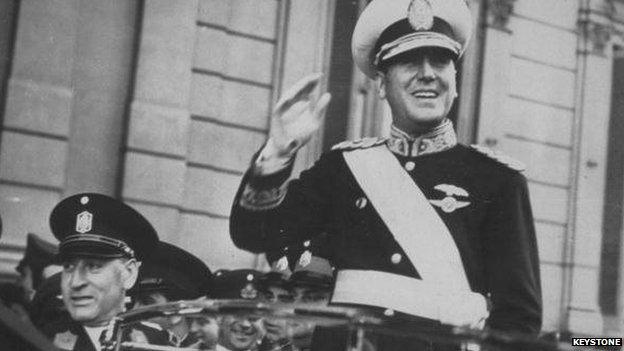 Juan D Peron, smiling from his car, on his way to assume the Argentine Presidency.