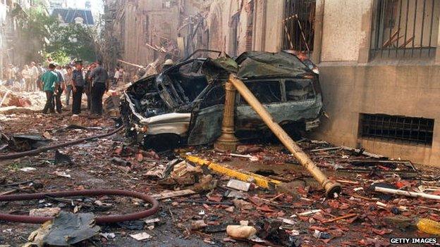 Police and rescue workers stand near destroyed cars and debris on March 17, 1992 in Buenos Aires shortly after a powerful bomb ripped through the Israeli embassy.