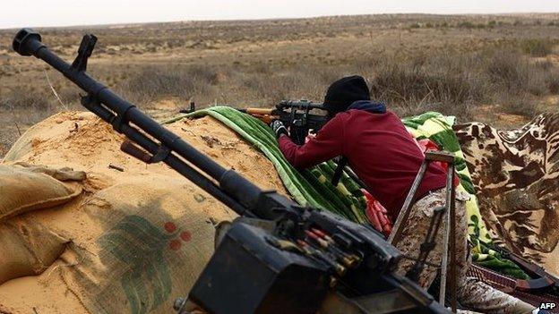 A fighter of the Libya Dawn militia aims his weapon during clashes with forces loyal to Libya's internationally recognised government near the Wetia military air base