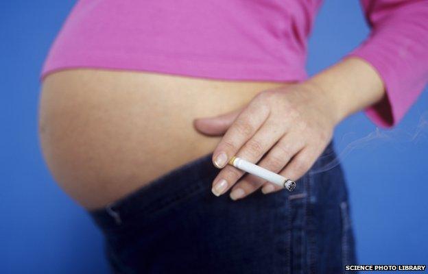 Pregnant woman's stomach and her holding a cigarette