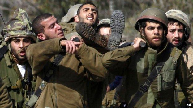 Israeli soldiers carry a wounded comrade near the Lebanese border (28 January 2015)