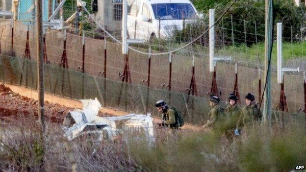 Israeli troops inspect the wreckage of a military vehicle that was hit by a missile fired by Hezbollah militants in Shebaa Farms area (28 January 2015)