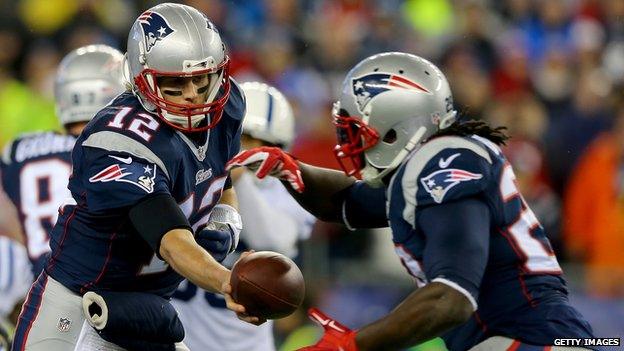 Tom Brady gives the ball to a running back