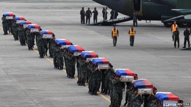 Members of the Philippine National Police's (PNP) Special Action Force (SAF) unit carry metal caskets containing the bodies of slain SAF police who were killed in Sunday's clash with Muslim rebels, upon arriving at Villamor Air Base in Pasay city, metro Manila on 29 January 2015