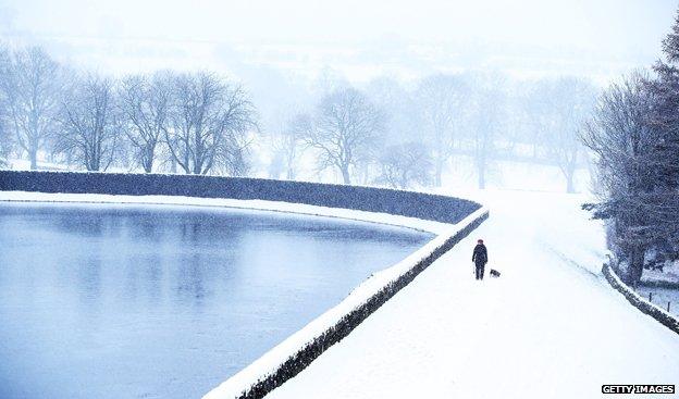 Solitary figure walking by frozen lake