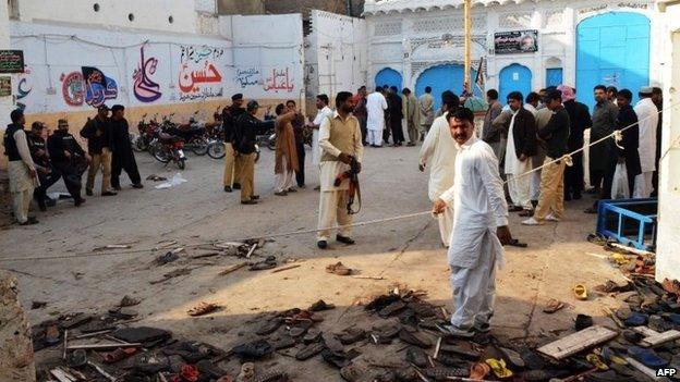 Pakistani security officials gather at the scene following a bomb attack at a Shiite Muslim mosque in Shikarpur in Sindh province