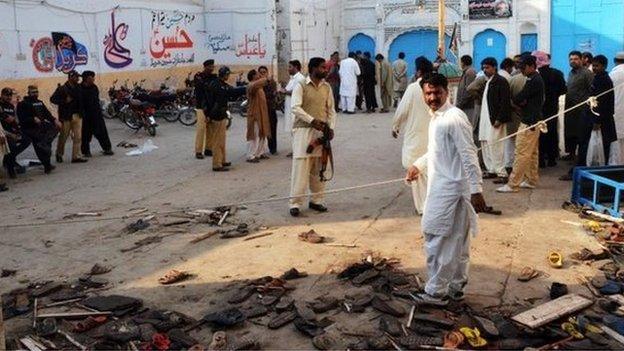 Pakistani security officials gather at the scene following a bomb attack at a Shiite Muslim mosque in Shikarpur in Sindh province