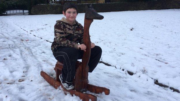 Boy on a sledge that looks like a giraffe with a jackal's head