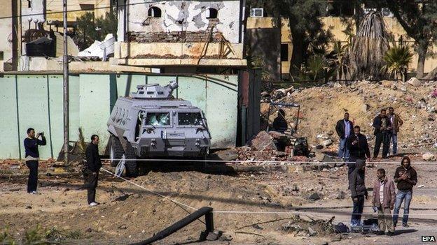 Egyptian security officers and local residents inspect the damage caused by the attack in El-Arish, 30 January 2015