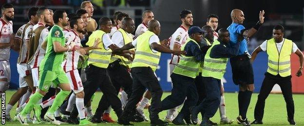 Security guards protect referee Rajindraparsad Seechurn from Tunisia's players