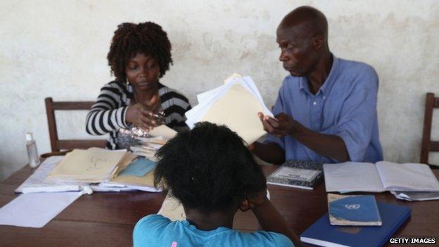 A mother registers her children with school officials in the West Point township of Monrovia (29 January 2015)