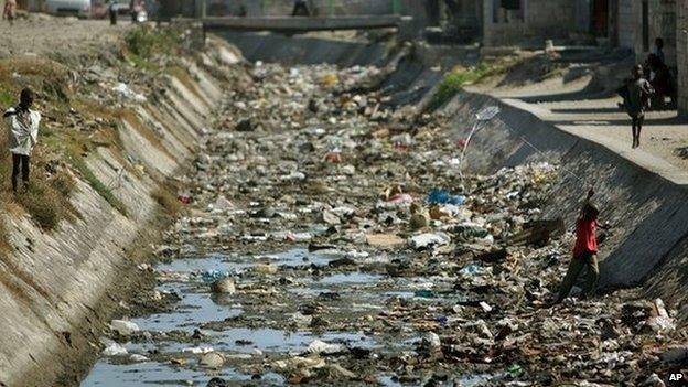 Haitian boys launch kites inside a refuse-strewn sewer canal in Cite Soleil, Port au Prince, Haiti