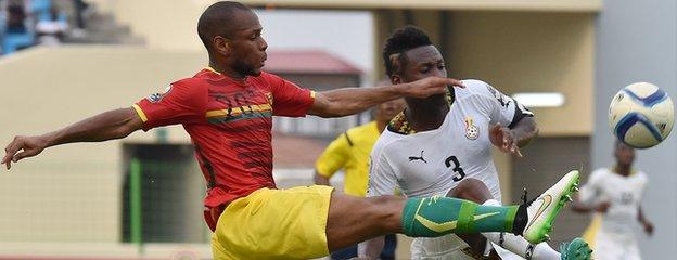 Guinea defender Baissama Sankoh (left) challenges Ghana forward Asamoah Gyan