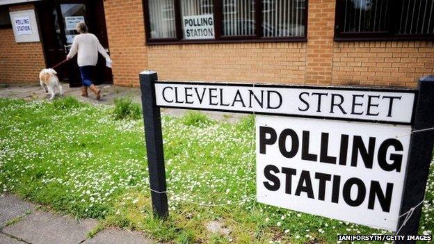 A woman enters a polling station on the day of the local and European elections in May 2014