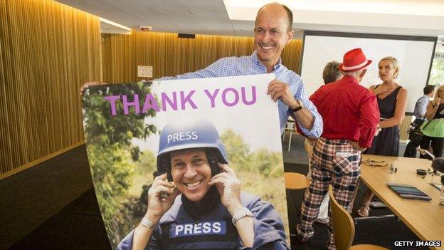 Peter Greste's brother Peter holds a poster of his brother as he celebrates the journalist's release at a press conference in Brisbane