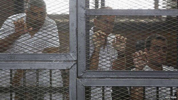 Al Jazeera journalists (L-R) Mohamed Fahmy, Peter Greste and Baher Mohamed stand behind bars at a court in Cairo in this May 15, 2014 file photo