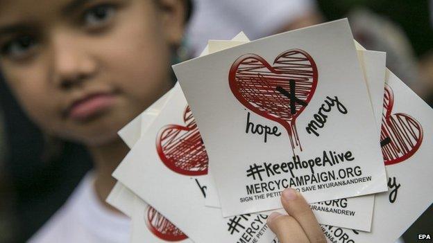 A child holds stickers of a campaign to save two Australian citizens from death sentence, in Bali, Indonesia, 31 January 2015.