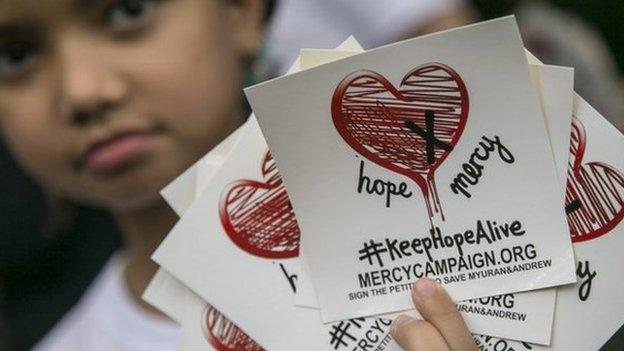 A child holds stickers of a campaign to save two Australian citizens from death sentence, in Bali, Indonesia, 31 January 2015.