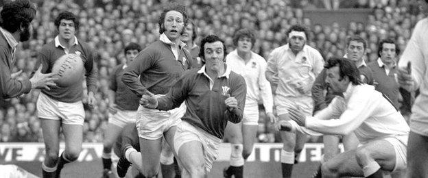 Wales' Phil Bennett sends out a pass against England in 1976, as JPR Williams looks on