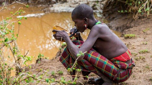 African girl drinking water through filter straw to prevent Guinea worm disease