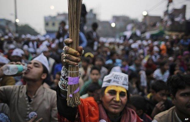 A supporter of Aam Aadmi Party, or Common Man Party, holds up a broom, the party symbol, as their leader Arvind Kejriwal addresses an election rally in New Delhi, India, Tuesday, Feb. 3, 2015