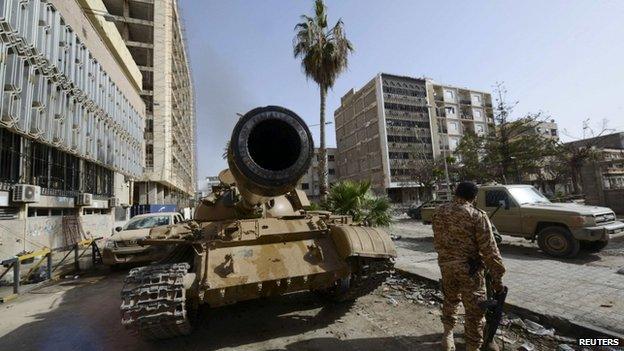 A member of the Libyan pro-government forces, backed by locals, stands near a tank outside the Central Bank, near Benghazi port, January 21, 2015.