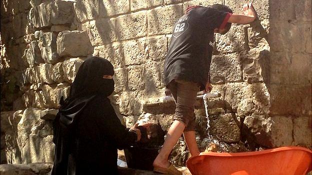 Woman and child washing dishes in Sanaa