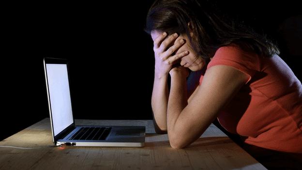 Woman covering her face while on laptop