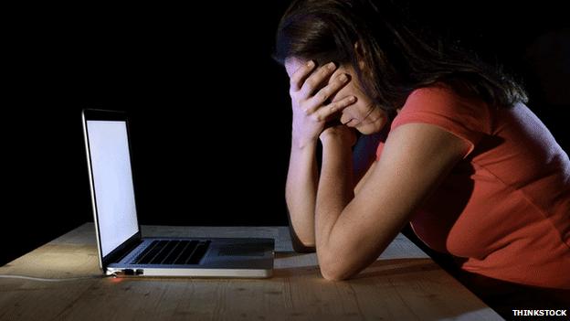 Woman covering her face while on laptop