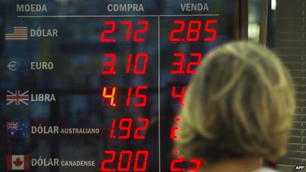 A woman looks at the exchange rate board of a bureau de change in Rio de Janeiro, Brazil, on February 4, 2015