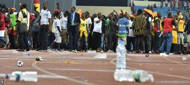 Bottles and other objects lie on the running track next to the pitch