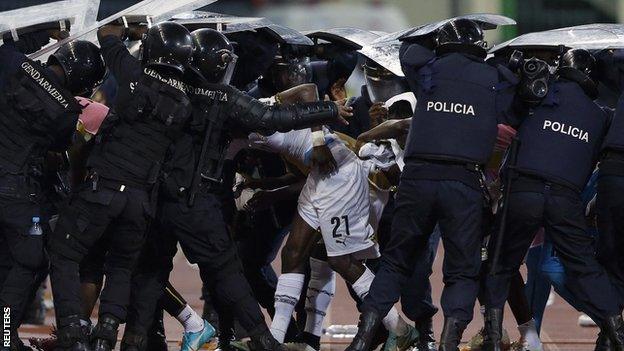 Police in riot gear attempt to protect Ghana players as they leave the pitch