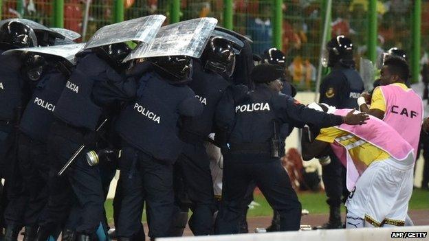 Ghana players leave the pitch at half time protected by riot police