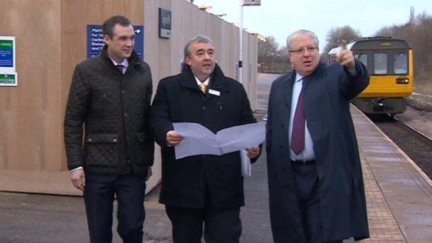 Transport Secretary Patrick McLoughlin on station platform with Pacer train pulling in