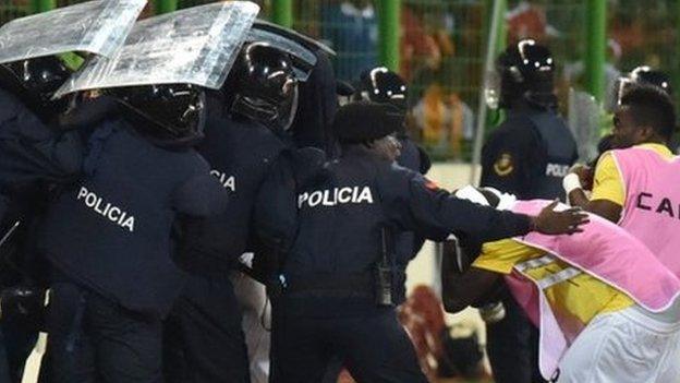 Ghana players leave the pitch at half time protected by riot police