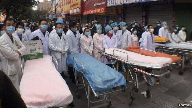 Medical personnel wait next to stretchers after a fire broke out at a wholesale market building in Huidong county, Guangdong province February 5, 2015