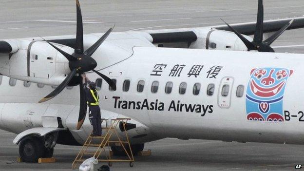 A ground mechanic works on the engine area of a TransAsia Airways ATR airplane at Songshan Airport in Taipei, Taiwan, 7 February 2015