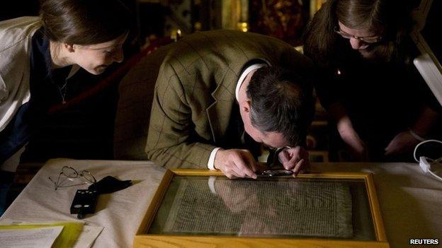 A parliamentary archive conservator examines the Salisbury copy of the Magna Carta