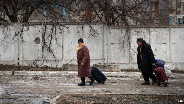 People walk with their belongings on February 7, 2015 in the eastern Ukrainian town of Vuglegirsk in the Donetsk region